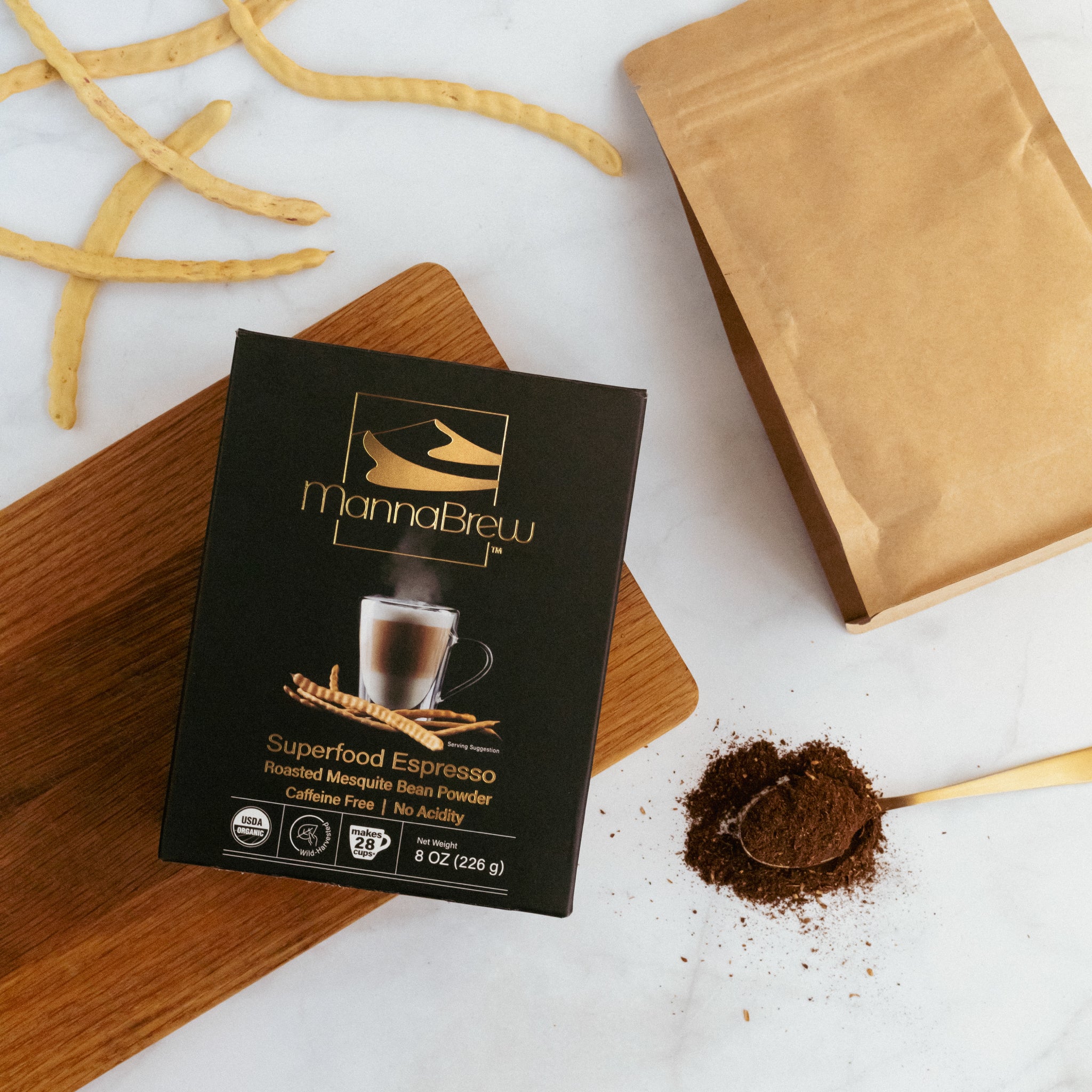 MannaBrew Superfood Espresso package on a white surface with ground mesquite bean powder and a spoon.