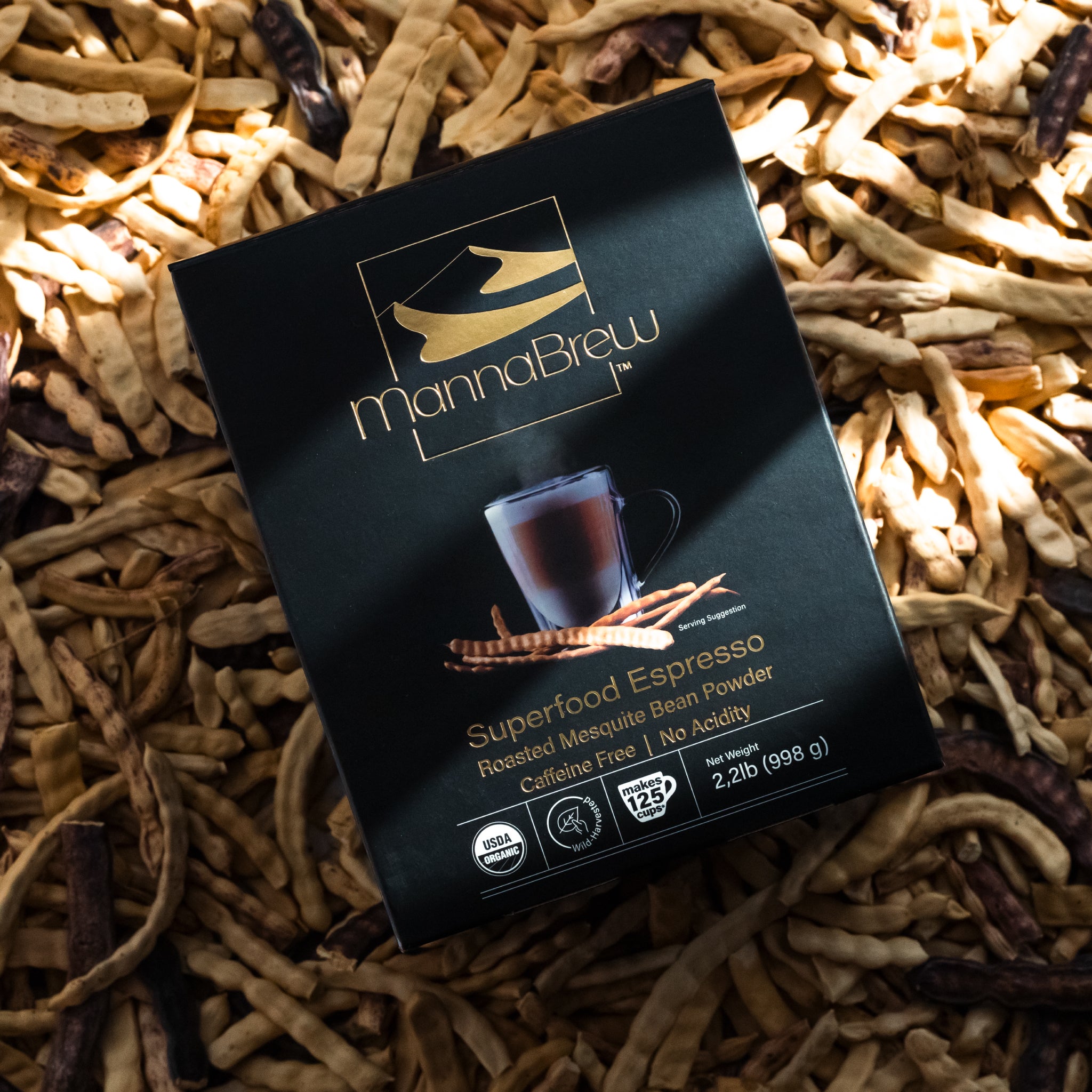 MannaBrew Superfood Espresso package on a background of mesquite pods