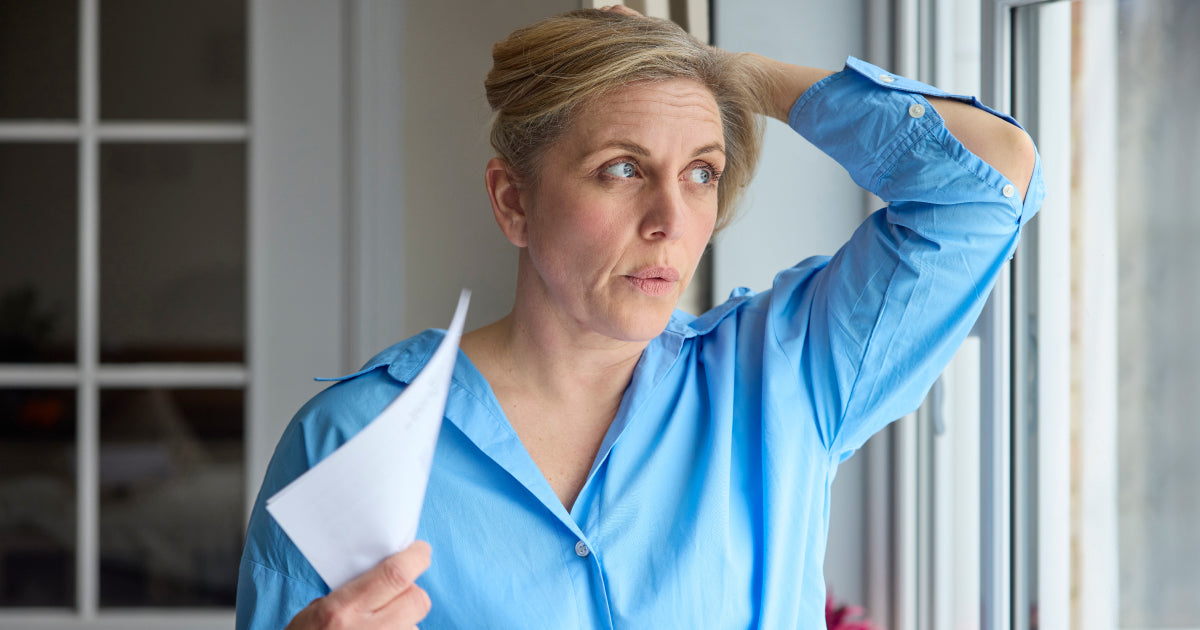 Woman Holding her head and fanning herself with a piece of paper