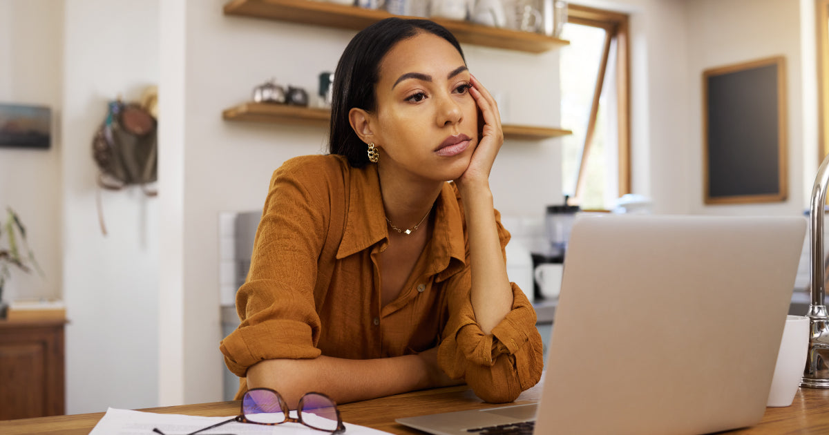 A woman siting behind her laptop, tired, head on hand