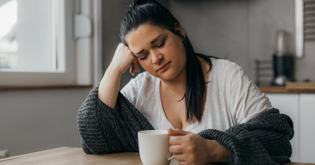 A woman sitting in front of her coffee, tired