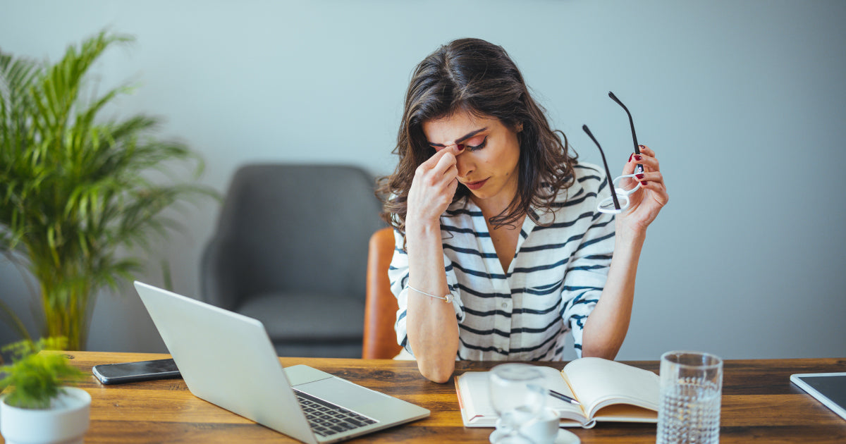 Woman holding head at laptop