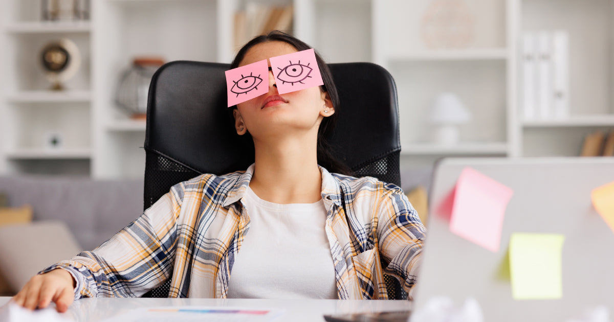 Person napping at their desk with post it notes covering their eyes.