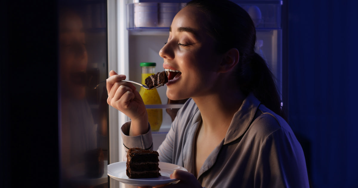 Woman snacking in front of the fridge, late at night